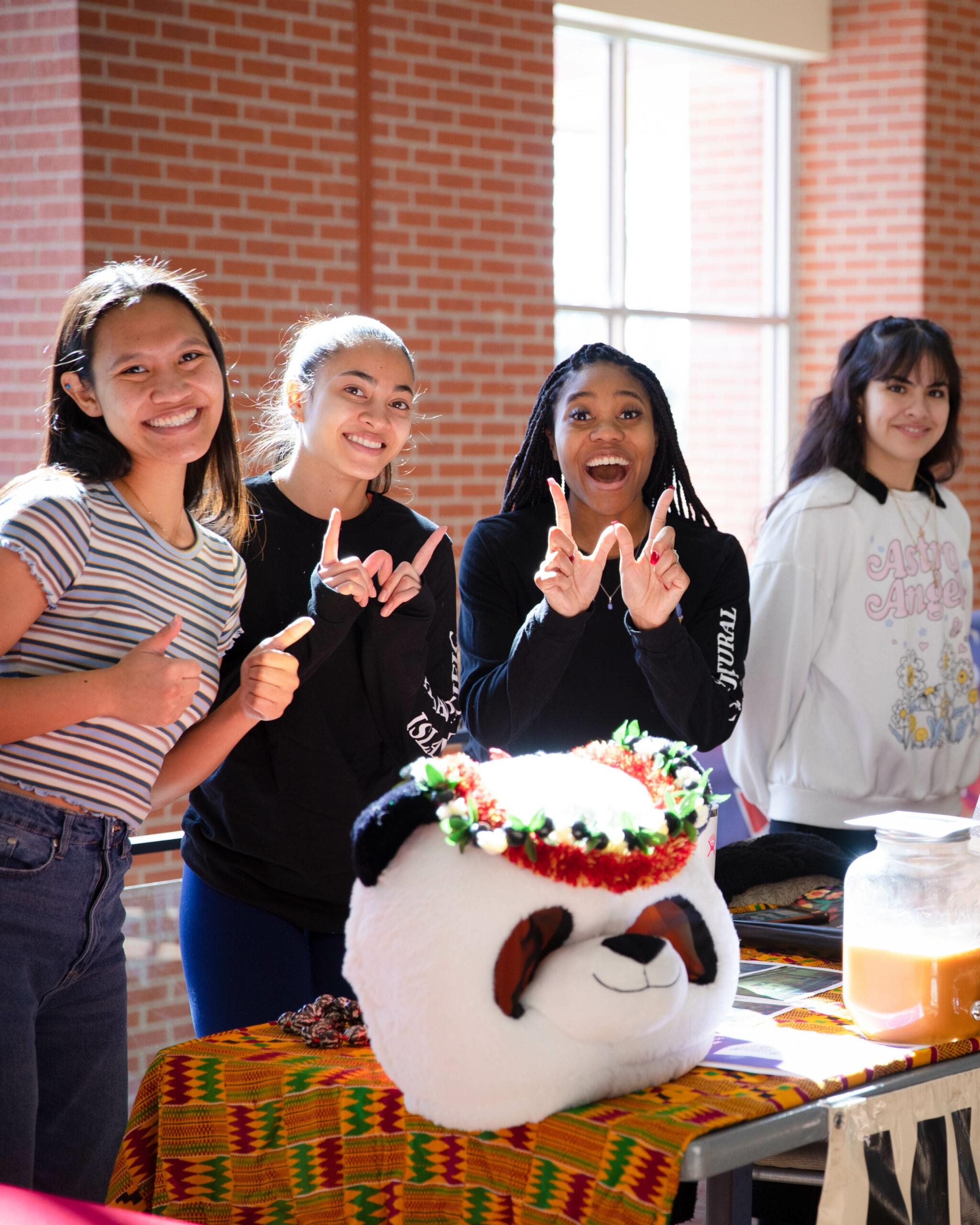 A few students pose for a photo behind a table.